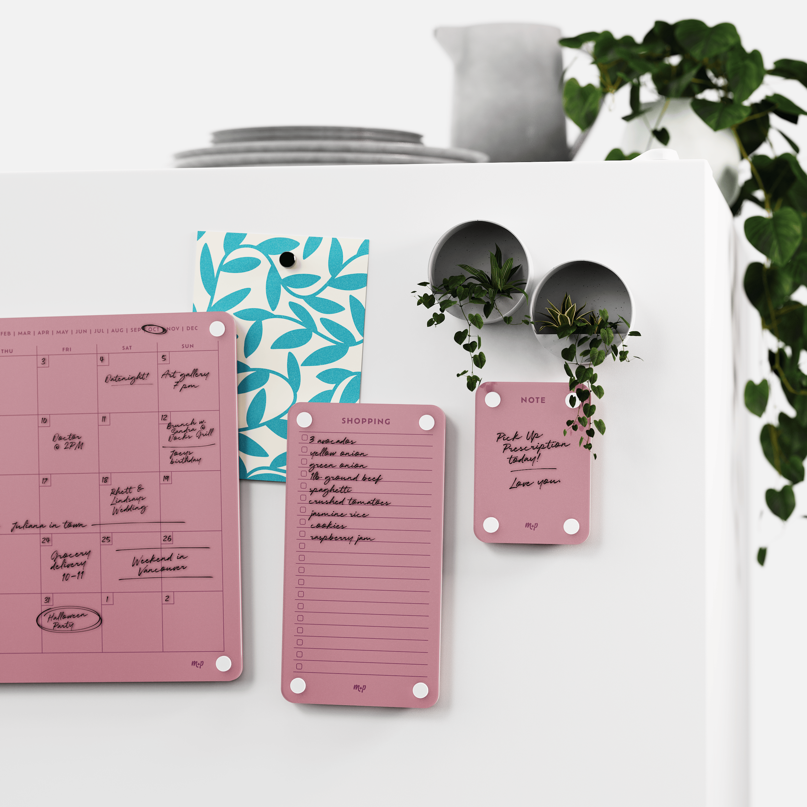 Plum calendar, shopping list and note board on a white wall beside two magnetic planters